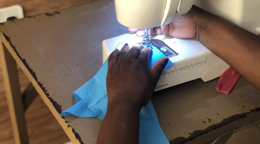 Foto mostrando uma mão utilizando uma máquina de costura
